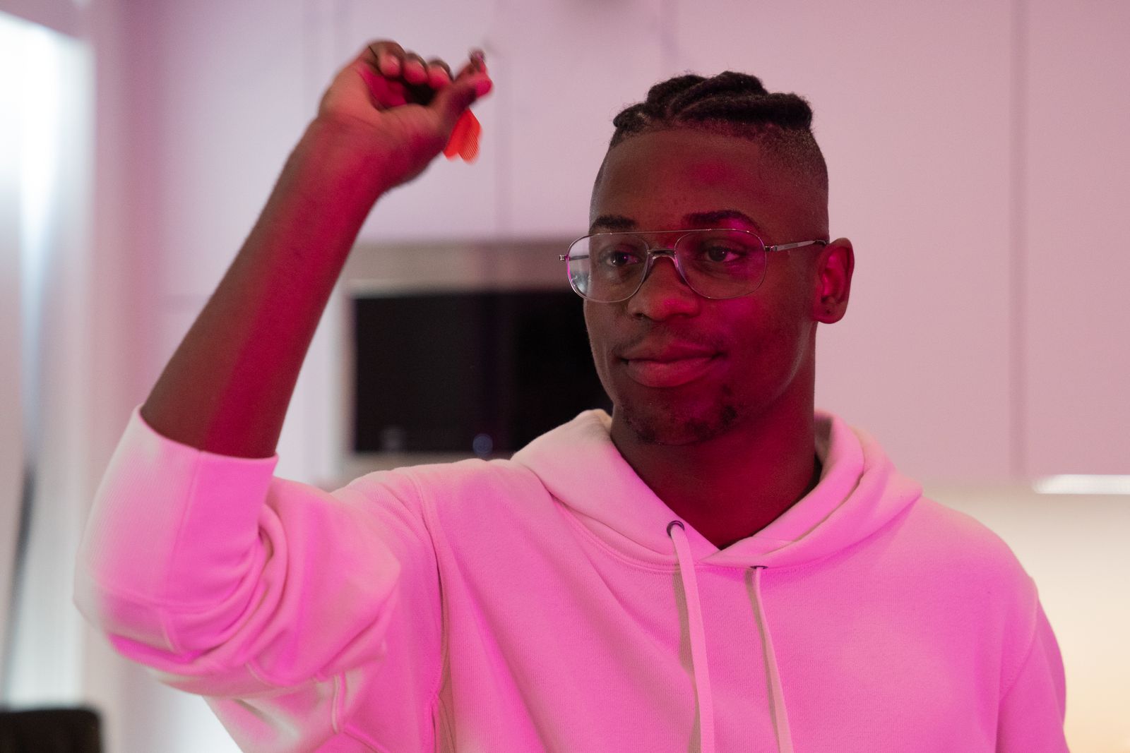 Player lining up a dart throw under magenta light