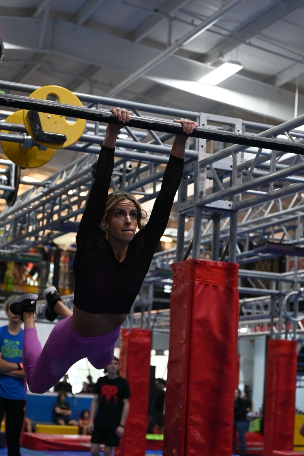 Athlete swinging across a ninja obstacle-course rig