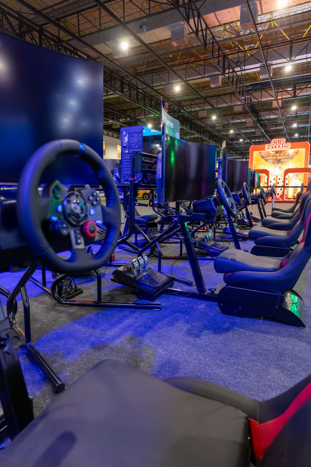 Racing simulator rigs with wheels and pedals under blue neon light